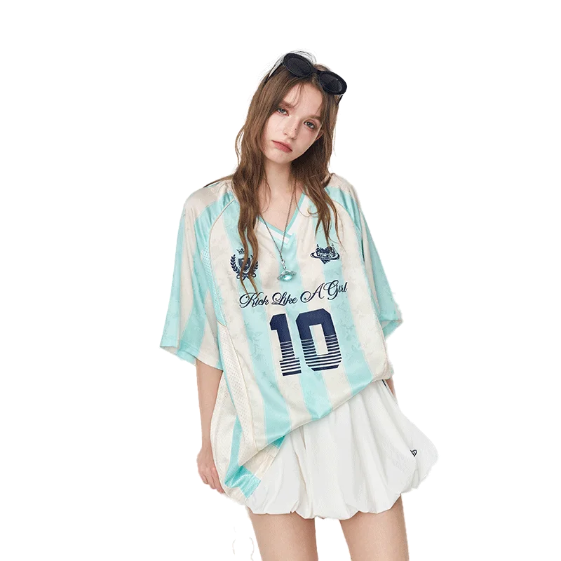 A woman modeling a light blue and white tie-dye short-sleeve t-shirt with a dark blue number 10 and 'Fish Like A Girl' text, paired with a white pleated skirt against a solid white background.