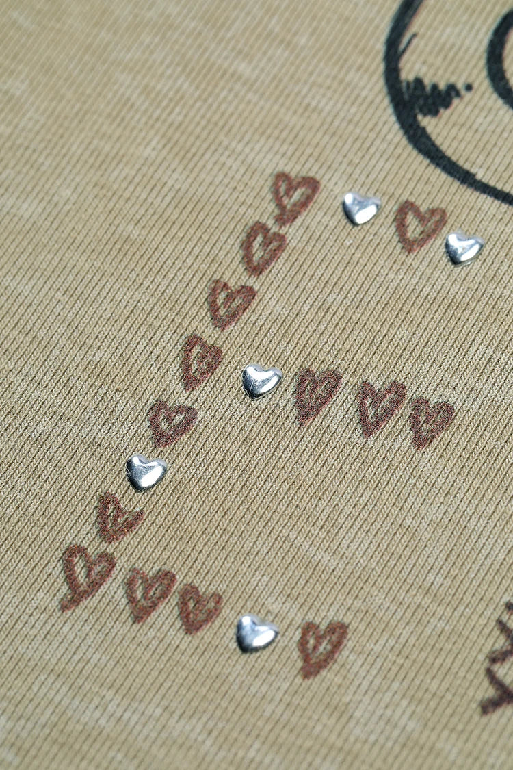 A close-up of a beige fabric surface with a decorative arrangement of small brown hearts and several shiny silver heart-shaped embellishments.