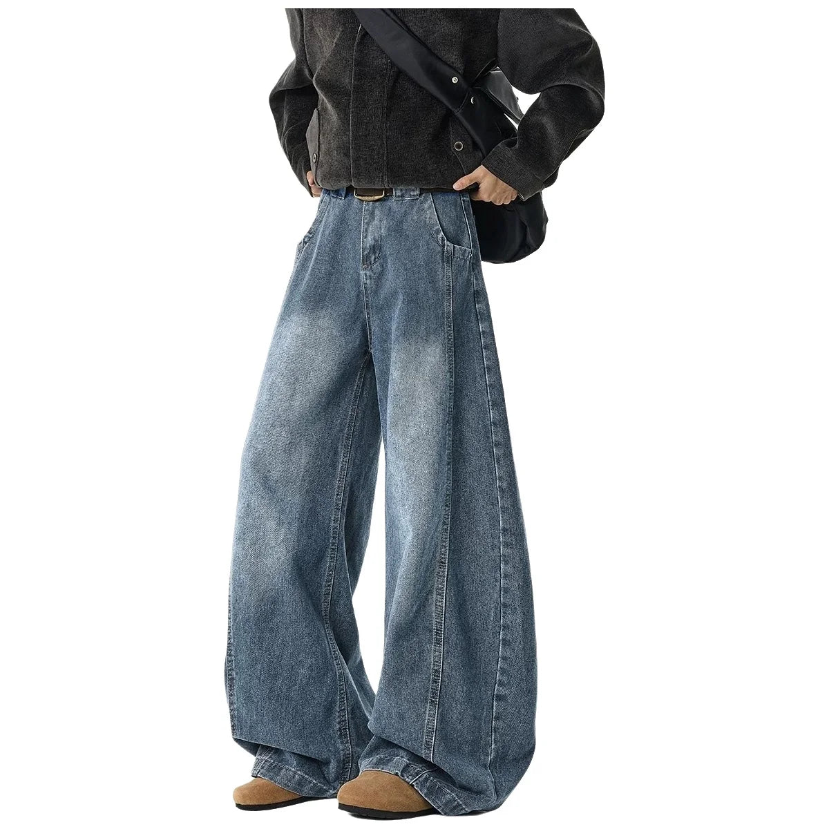 A person wearing wide-leg blue denim jeans with a black corduroy jacket, brown shoes, and a black shoulder bag, shown from the chest down on a plain white background.