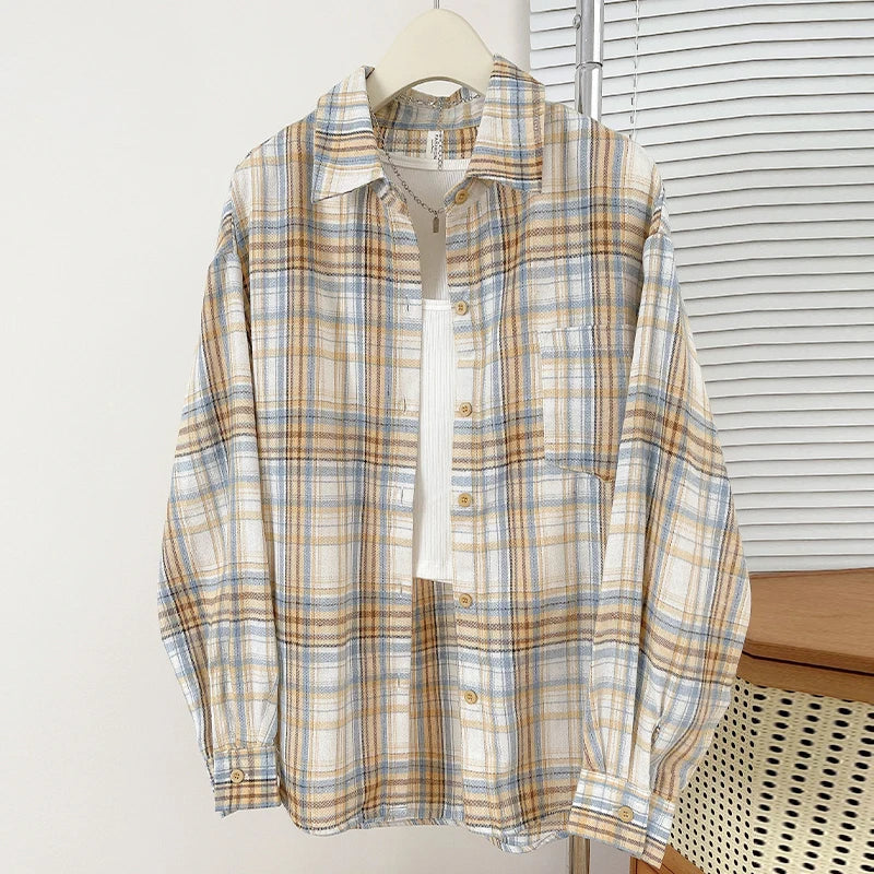 Plaid shirt on a hanger against a white wall with a window in the background
