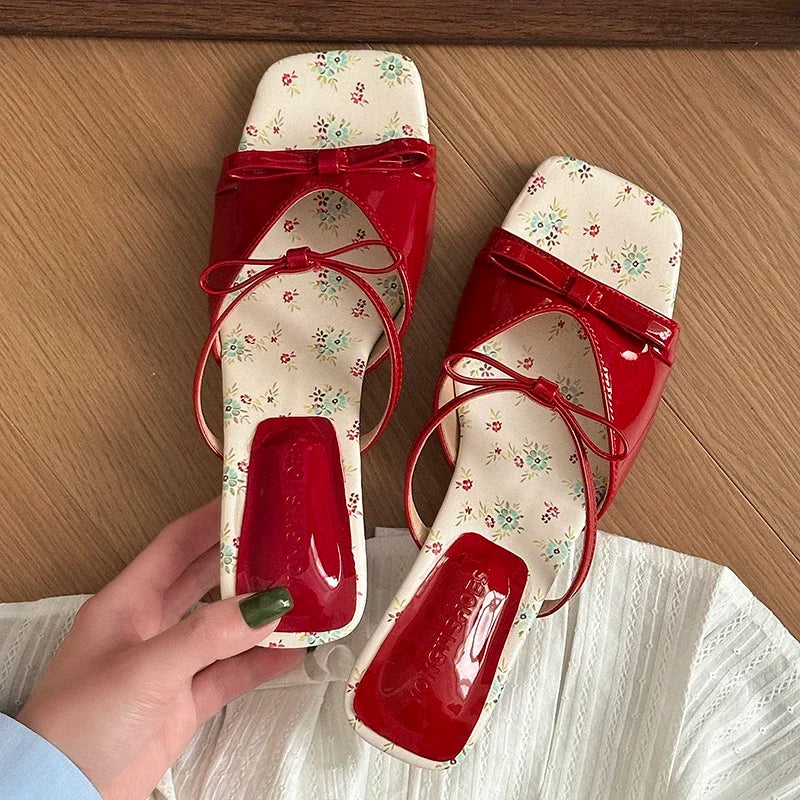 Red sandals with floral pattern on a wooden surface