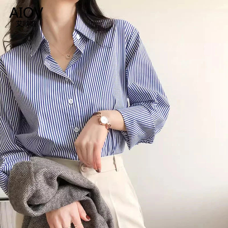 Person wearing a blue and white striped shirt with a neutral background