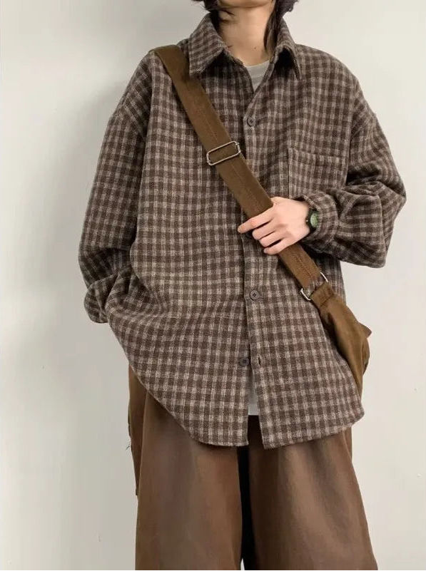 Person wearing a brown plaid shirt and brown pants with a brown bag over one shoulder against a white background.