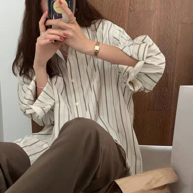 Person wearing a striped shirt and brown pants sitting indoors.