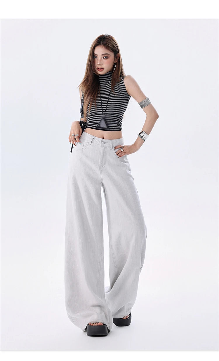 A model posing in a black and white striped crop top and light gray wide-leg pants against a plain white studio background.