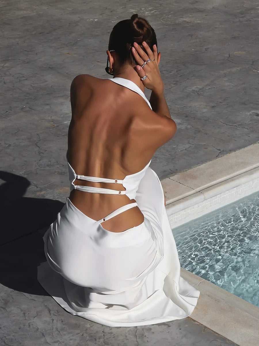 Woman in a white dress sitting by a pool