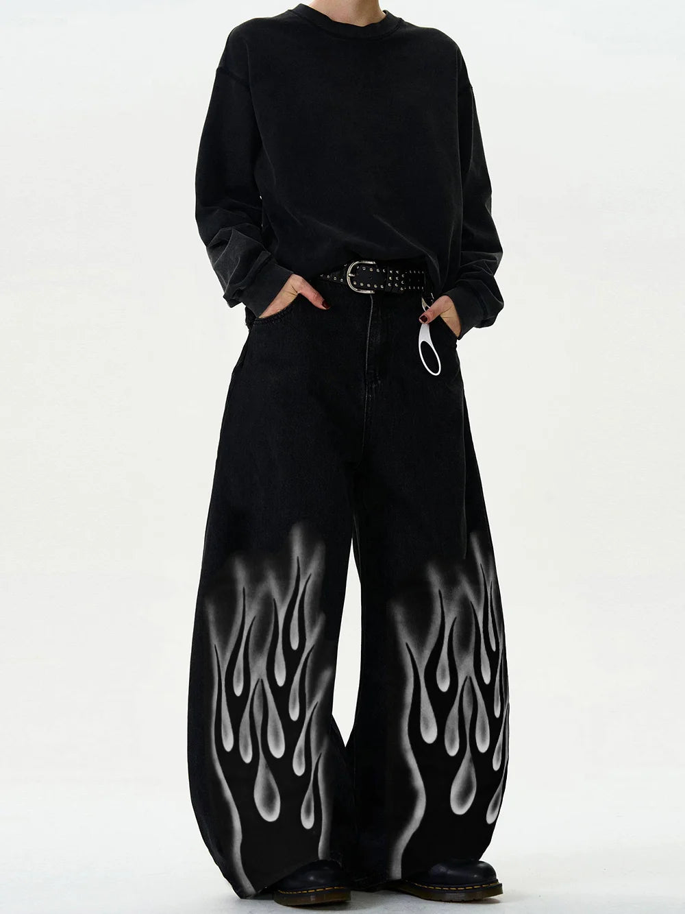 Person wearing a black outfit with flame designs on pants against a white background