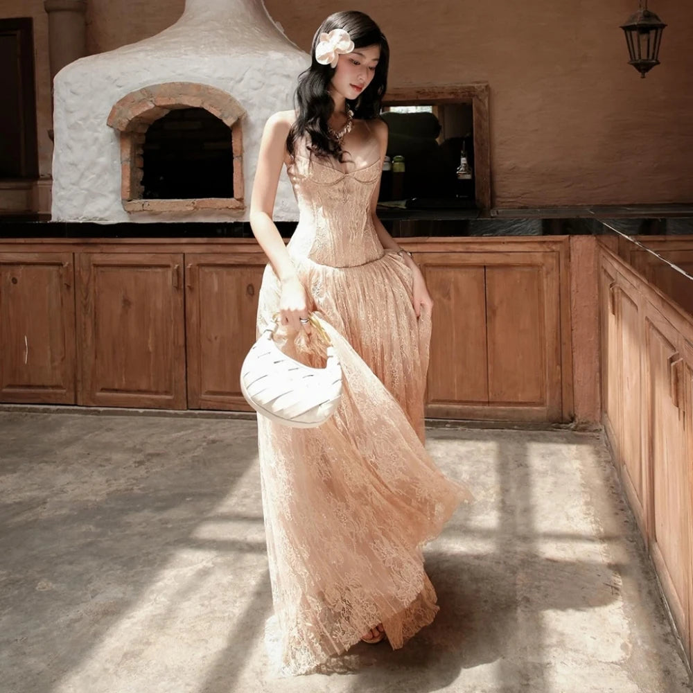 Woman in a long, light-colored dress standing in a rustic kitchen.