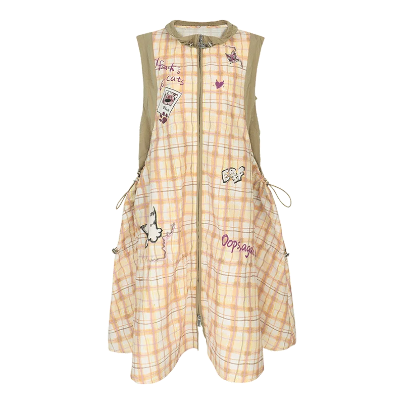 A sleeveless, front-zip A-line dress with a light peach and white plaid pattern, decorated with various cartoon stickers, patches, and handwritten text, featuring beige shoulder straps.
